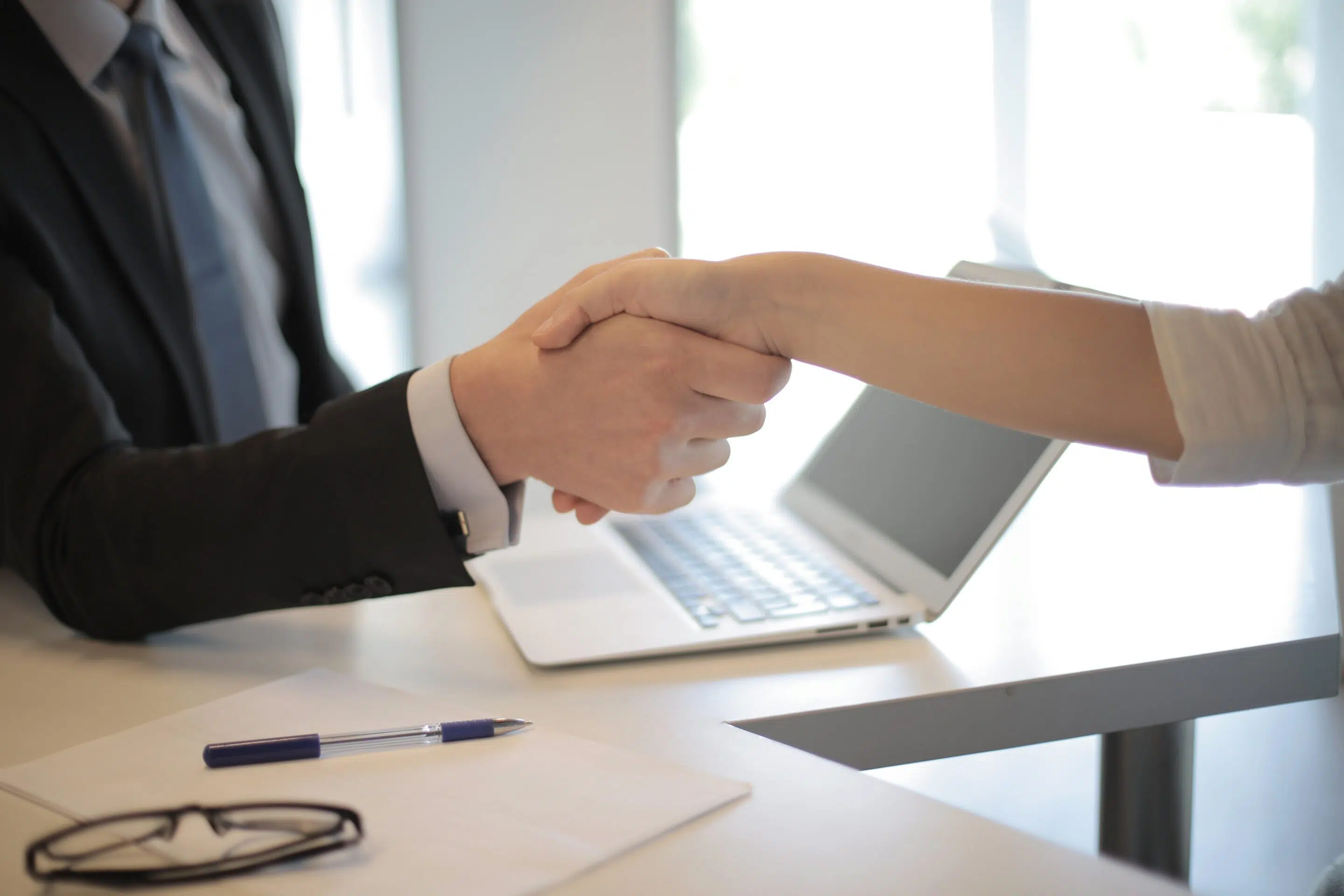 Handshake_over_desk_with_laptop
